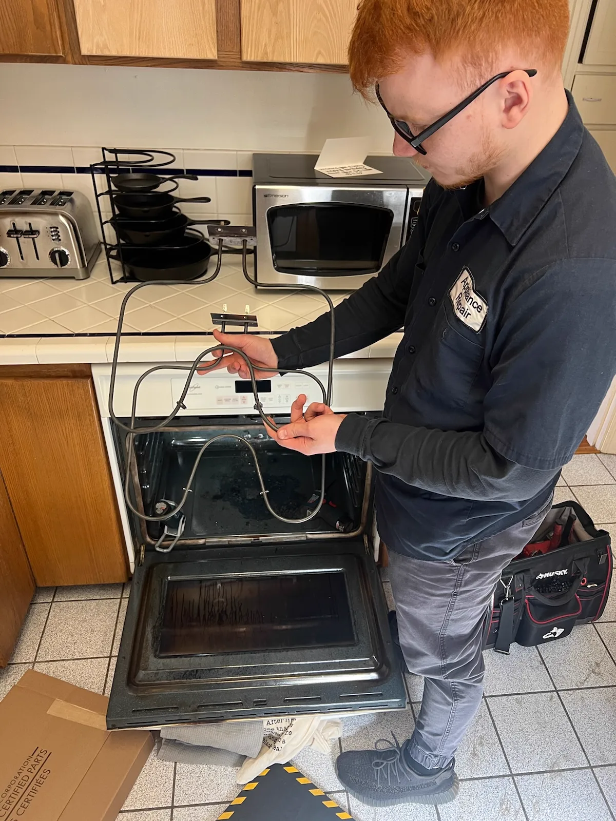 Technician replacing a bake element in an oven at a King County home